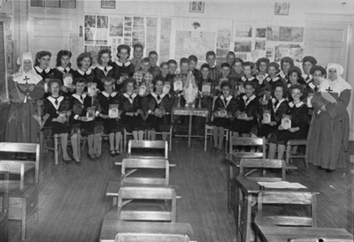 Reproduction d'une photographie des &eacute;l&egrave;ves de soeur Eva Perrault, f.d.l.s., et de soeur Rose Boudreault, f.d.l.s., &agrave; l'&eacute;cole Saint-Joseph de Blind River, Ontario, ca 1960.