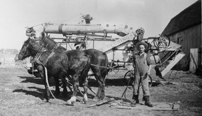 Reproduction d’une photographie de David Deguire &agrave; cot&eacute; d’un moulin &agrave; battre &agrave; la ferme de William Malette, Lochiel (Ontario), 1945.