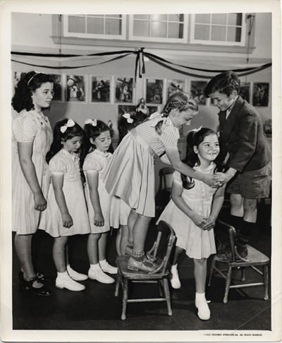 Reproduction d’une photographie de Th&eacute;r&egrave;re, Pauline et Daniel Dionne s’amusant avec leurs soeurs, les jumelles Dionne, 1941.
