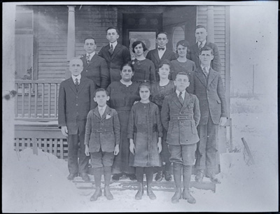 Reproduction d’une photographie de la famille de Napol&eacute;on Demers, dont tous les enfants travaillent &agrave; la Empire Cotton Mill, devant leur domicile, une maison appartenant &agrave; la compagnie, Welland (Ontario), ca 1920.