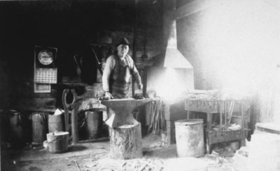 Reproduction d’une photographie de Th&eacute;odule Lalonde dans sa boutique de forge, Plantagenet (Ontario), 1947.