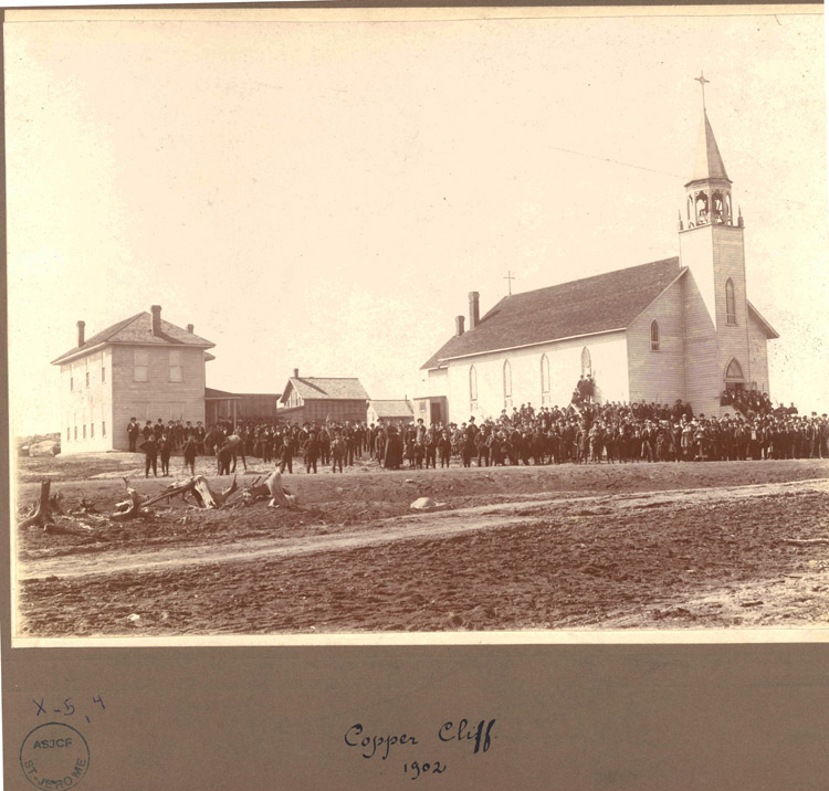 Reproduction d’une photographie de la population devant l’&eacute;glise Saint-Stanislas &agrave; Cooper Cliff (Ontario), 1902.